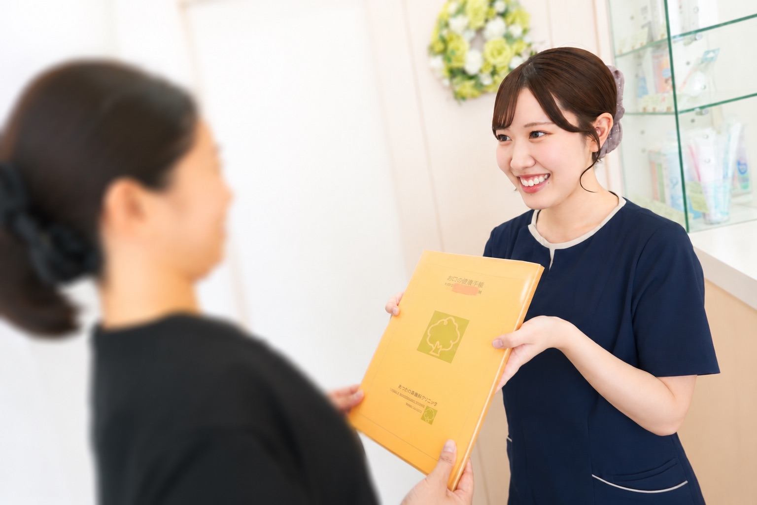 お口の健康手帳を患者さまにお渡しするあつたの森歯科クリニックの歯科衛生士