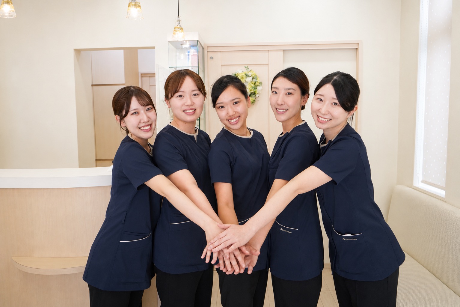 手を重ねるあつたの森歯科クリニックのスタッフ
